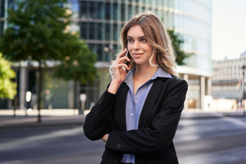Portrait of successful businesswoman, company ceo walks on street and makes phone calls, talking on